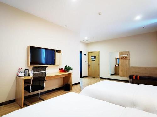 - une chambre avec un lit et un bureau avec une télévision dans l'établissement 7Days Premium Ordos City Government Branch, à Ordos