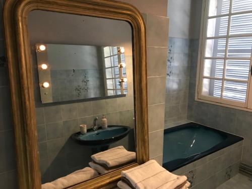 a bathroom with a tub and a sink and a mirror at La pause nuitonne in Nuits-Saint-Georges