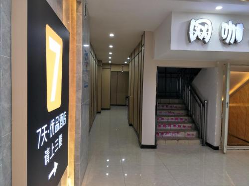 a hallway with a staircase in a building with a sign at 7Days Premium Xining Bayi East Road Tuanjie Bridge Branch in Xining