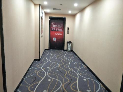a hallway with a door and a carpeted floor at 7Days Premium Xining Bayi East Road Tuanjie Bridge Branch in Xining