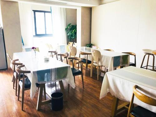 a dining room with tables and chairs with white tablecloths at 7Days Premium Chengdu Pi County Xiqu Avenue Branch in Chengdu