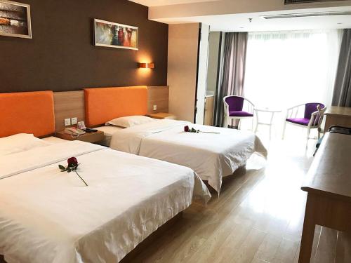 2 letti in una camera d'albergo con fiori di 7Days Premium Chengdu Pi County Xiqu Avenue Branch a Chengdu