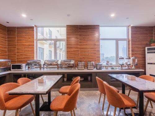 Xingtaiにある7 Days Premium Xingtai Ruihe City Branchのキッチン(テーブル2台、オレンジチェア付)