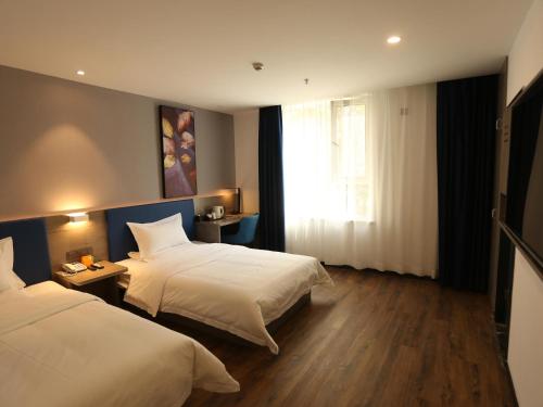 a hotel room with two beds and a window at 7Days Premium Xi'ning Dashizi Center Branch in Xining