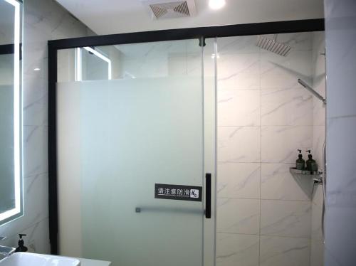 y baño con ducha y puerta de cristal. en 7Days Premium Zhumadian Tianzhongshan Avenue Branch, en Zhumadian