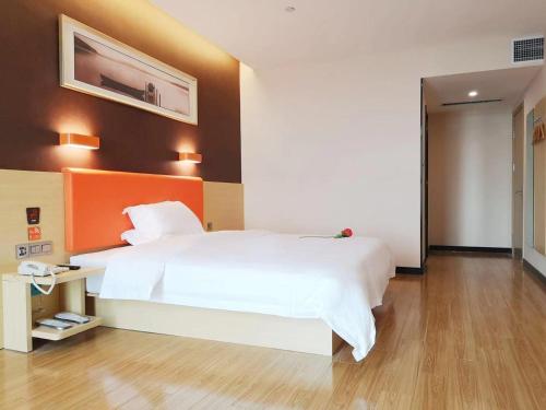 a bedroom with a large white bed with an orange headboard at 7Days Premium Heze Train Station Branch in Heze