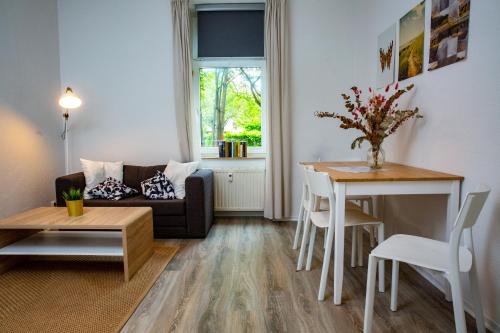 een woonkamer met een bank en een tafel bij Ruhiges City Apartment "Altbauperle" mit Charme und 2 Schlafzimmern in Erfurt