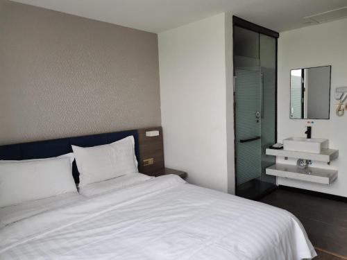 a bedroom with a large white bed and a sink at 7Days Premium Shangdi Tiyu University Branch in Beijing