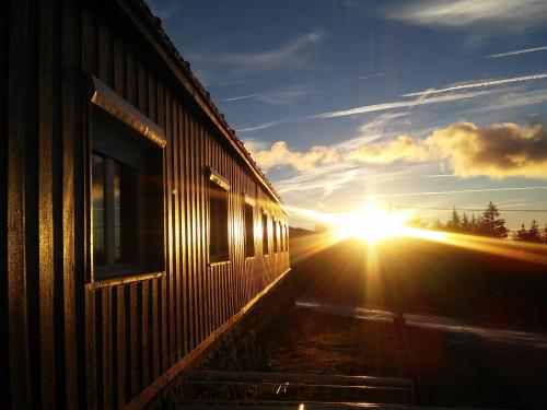 a sun is setting next to a building at HI Serra da Estrela - Pousada de Juventude in Penhas da Saúde
