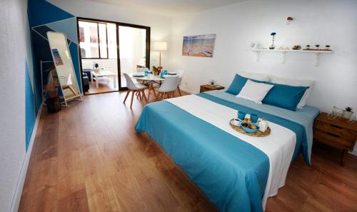 a blue and white bedroom with a bed and a table at Peaceful & Bright Loft, HEATED POOL, NETFLIX, FREE WIFI & PARKING, TENNIS in Los Cristianos