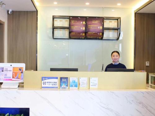 a man standing behind a counter in an office at 7Days Premium Xiong'an New District Rongcheng Baiyangdian Branch in Baoding
