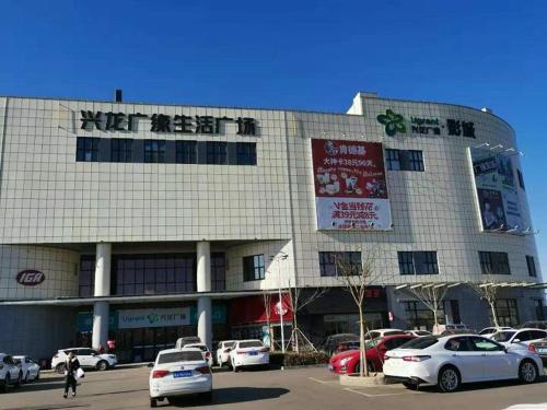 a large building with cars parked in a parking lot at 7Days Premium Qinhuangdao Lulong Bus Station Yongwang Avenue Branch in Qinhuangdao
