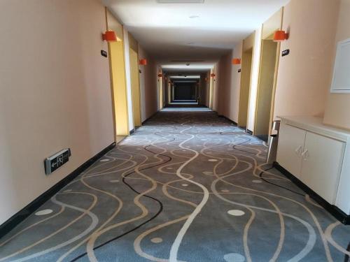 a hallway of a hotel with a carpet on the floor at 7Days Premium Qinhuangdao Lulong Bus Station Yongwang Avenue Branch in Qinhuangdao