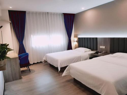 a hotel room with two beds and a blue chair at 7Days Premium Zigong Bus Terminal Branch in Zigong