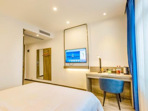 a hotel room with a bed and a desk and a tv at 7Days Premium Yibin North Gate Bus Station Branch in Yibin
