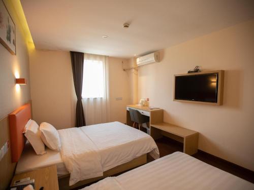 a hotel room with two beds and a flat screen tv at 7Days Premium Shanghai Xujiahui Longhua Road Subway Station Branch in Shanghai