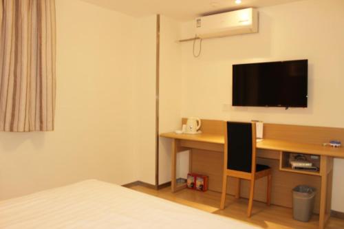 a hotel room with a desk and a television on the wall at 7Days Inn Deyang Wenmiao Square in Deyang