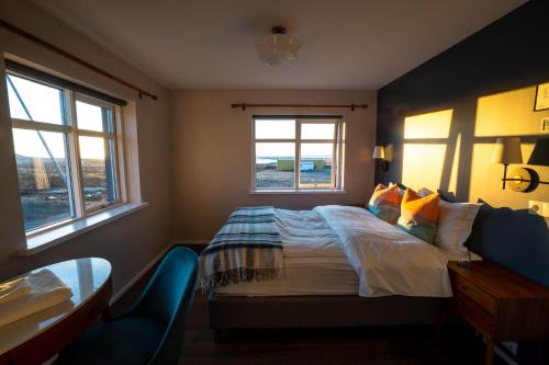 a bedroom with a bed and a desk and two windows at Soti Lodge in Fljot