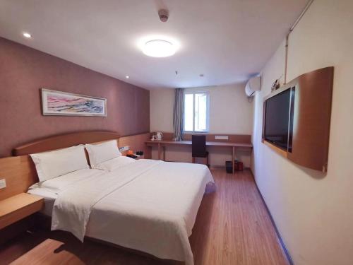 a bedroom with a large bed and a flat screen tv at 7Days Inn Guiyang Huaxi Avenue Zhong Cao Si in Guiyang