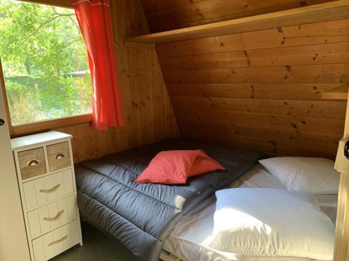 Ce lit se trouve dans une cabane en rondins dotée d'une fenêtre. dans l'établissement Camping Calme et Nature Iserand, à Vion