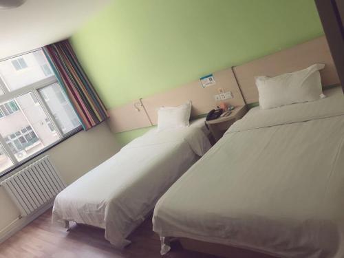 two beds in a hotel room with a window at 7Days Inn Xi'an Jiaoda Medical College Weiyi Street Subway Station in Xi'an