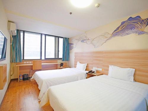 a hotel room with two beds and a mural on the wall at 7Days Inn Chengdu Shuangnan in Chengdu