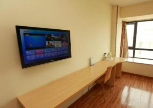 Habitación con escritorio y TV en la pared. en 7Days Inn Chengdu Chengyu Interchange Station, en Chengdú