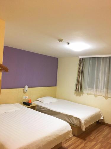 two beds in a room with a purple wall at 7Days Inn Changshou Road Subway station in Shanghai