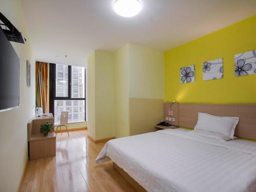 a bedroom with a white bed and a yellow wall at 7Days Inn Danyang Train Station Wuyue Square Branch in Zhenjiang