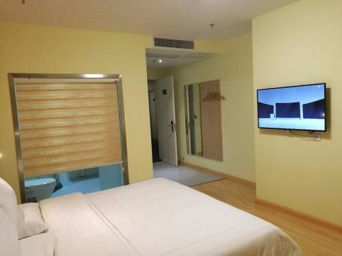 a bedroom with a bed and a flat screen tv at 7Days Inn Danyang Train Station Wuyue Square Branch in Zhenjiang