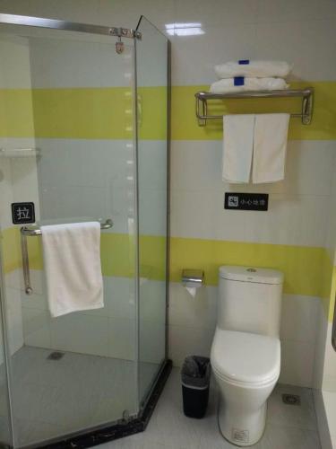 a bathroom with a shower and a toilet and towels at 7Days Inn Danyang Train Station Wuyue Square Branch in Zhenjiang