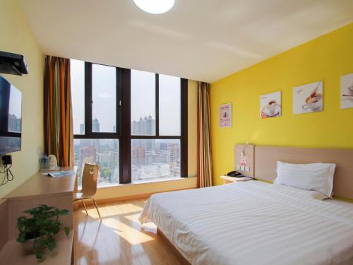 a bedroom with a large bed and a large window at 7Days Inn Danyang Train Station Wuyue Square Branch in Zhenjiang