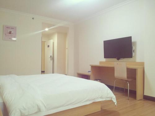 1 dormitorio con 1 cama y TV de pantalla plana en 7 Days Inn Foshan Pingzhou Jade Street Branch, en Foshan