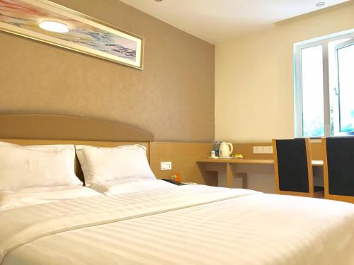 a bedroom with a large white bed and a window at 7Days Inn Chengdu Wuda Garden in Chengdu