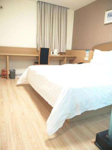 a bedroom with a large white bed and a desk at 7Days Inn Chengdu Wuda Garden in Chengdu