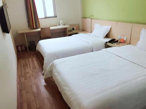 two beds in a hotel room with white sheets at 7Days Inn Nanjing Xuanwu Lake East Coach Terminal in Nanjing