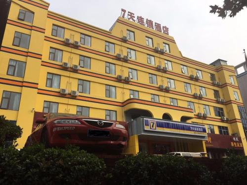 um edifício amarelo com um carro estacionado em frente em 7Days Inn Luoyang Xin'an Branch em Luoyang