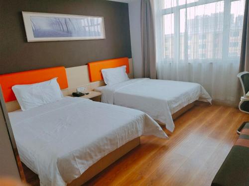 a hotel room with two beds and a window at 7Days Inn Hohhot Kaitai Market Branch in Hohhot