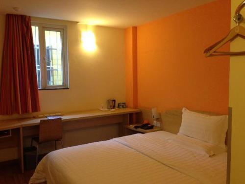 a bedroom with a bed and a desk and a window at 7Days Inn Kunming South Huancheng Road in Kunming