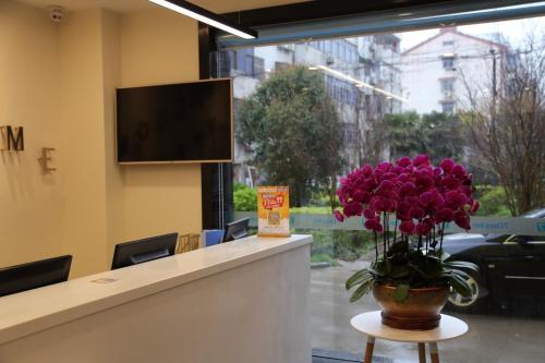 a lobby with a vase of purple flowers on a counter at 7 Days Hotel Taixing Wenchang Road Branch in Taizhou