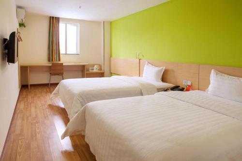 a hotel room with two beds and a green wall at 7Days Inn Yibin Boxi City Center Branch in Yibin