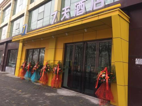 a yellow building with a row of women in colorful dresses at 7 Days Hotel Urumqi Kashgar East Road Normal University Branch in Ürümqi