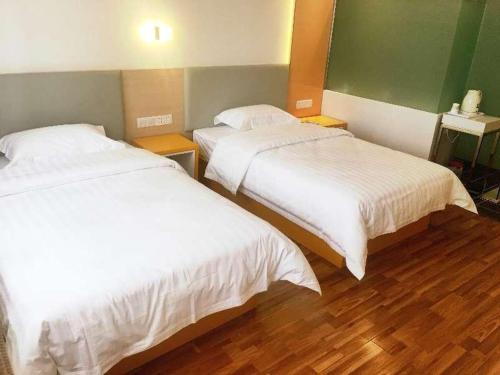 two beds in a room with wooden floors at 7 Days Hotel Urumqi Kashgar East Road Normal University Branch in Ürümqi