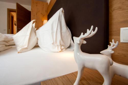 two white deer statues standing on a bed with pillows at Apartmenthaus Juen in Zams
