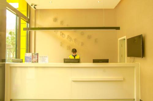 a person sitting at a counter with two laptops at 7Days Inn Chengdu Mianzhu Branch in Deyang
