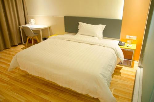 a bedroom with a large white bed and a desk at 7Days Inn Chengdu Mianzhu Branch in Deyang