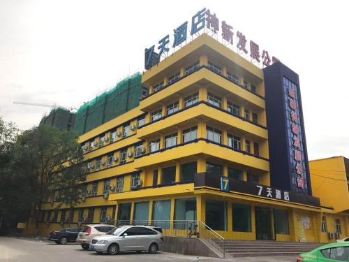 un edificio amarillo con coches estacionados frente a él en 7Days Inn Urumqi Midong Middle Road Shenhua Mining Bureau Branch en Ürümqi