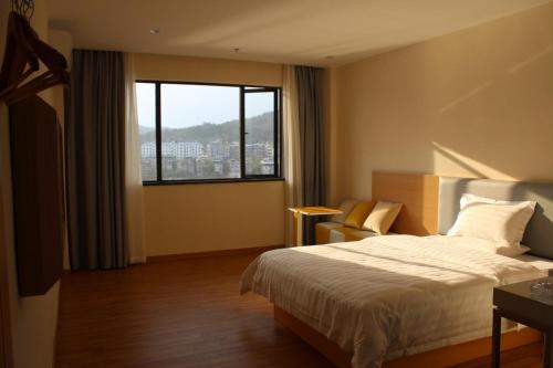 Habitación de hotel con cama y ventana grande en 7Days Inn Ganzhou Huichang Changshou Branch, 