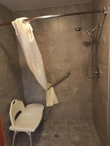 a shower with a shower curtain and a chair in a bathroom at Americas Best Value Inn - Temple in Temple