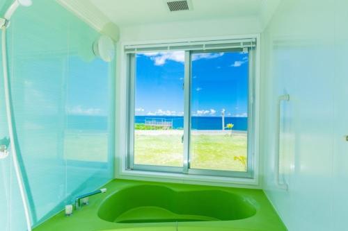 baño con lavabo verde y ventana en Condominium de Urmanchu / Vacation STAY 79737, en Nakijin